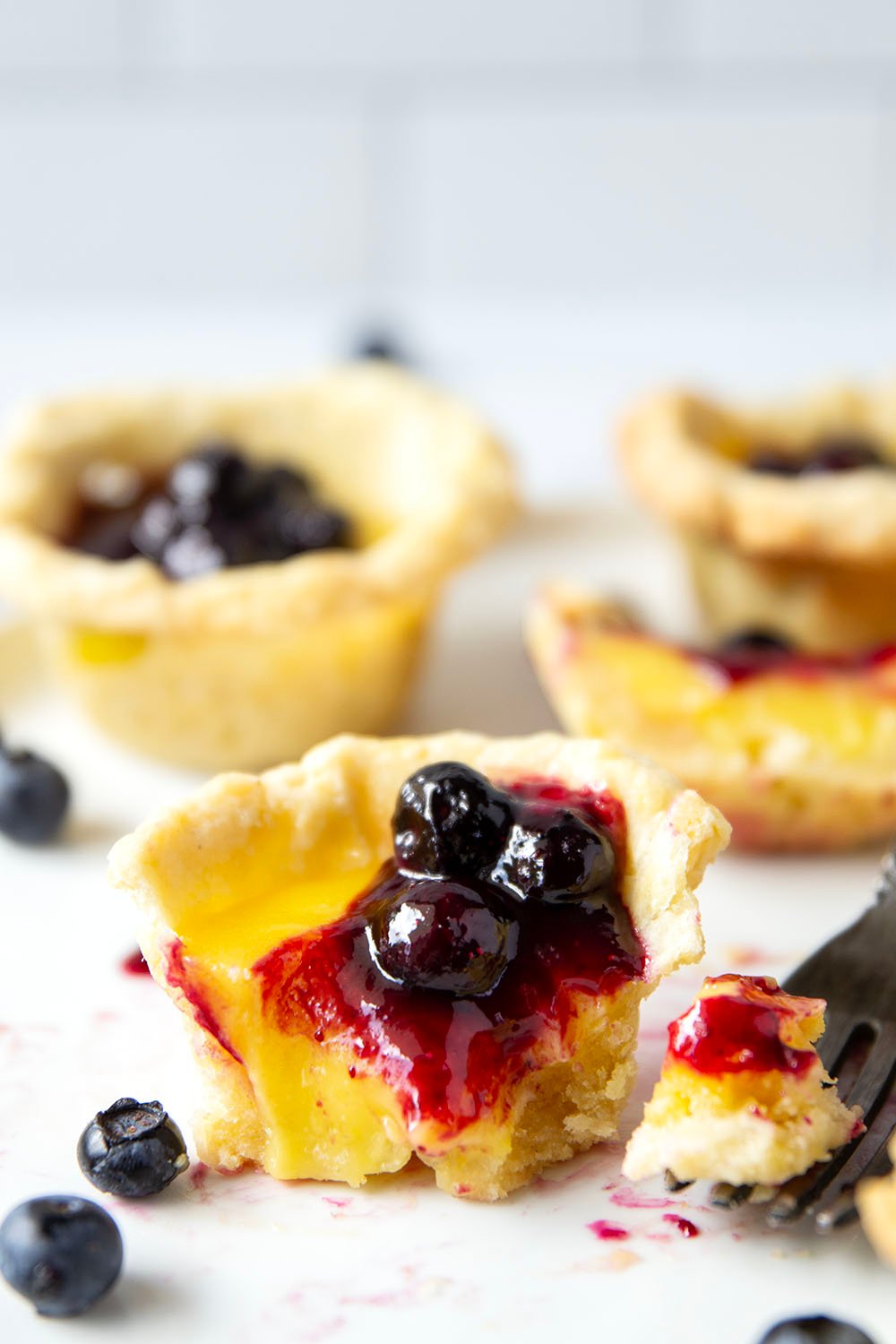 These mini lemon tarts feature a flaky pastry crust, tangy lemon filling, and lots of fresh blueberry sauce spooned on top.