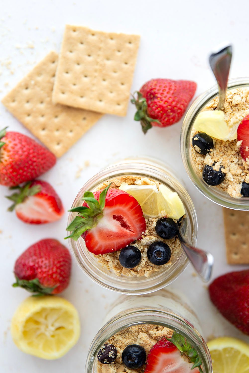 Layers upon layers of luscious lemon cheesecake, graham crackers, and lemon curd star in these no bake lemon cheesecake parfaits!
