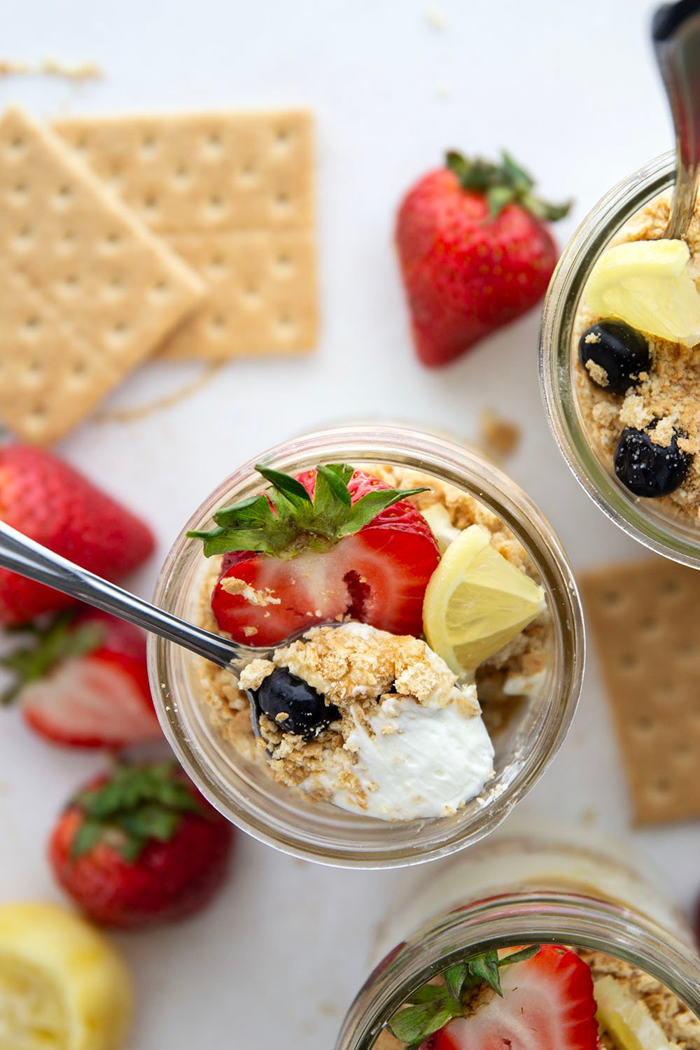 Layers upon layers of luscious lemon cheesecake, graham crackers, and lemon curd star in these no bake lemon cheesecake parfaits!