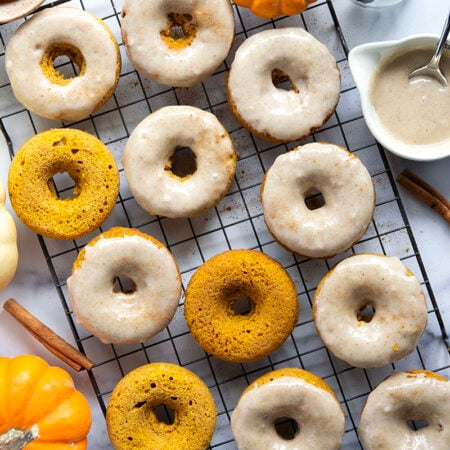 Super soft and fluffy baked pumpkin donuts are dipped in a rich cream cheese glaze and perfect for any fall occasion.