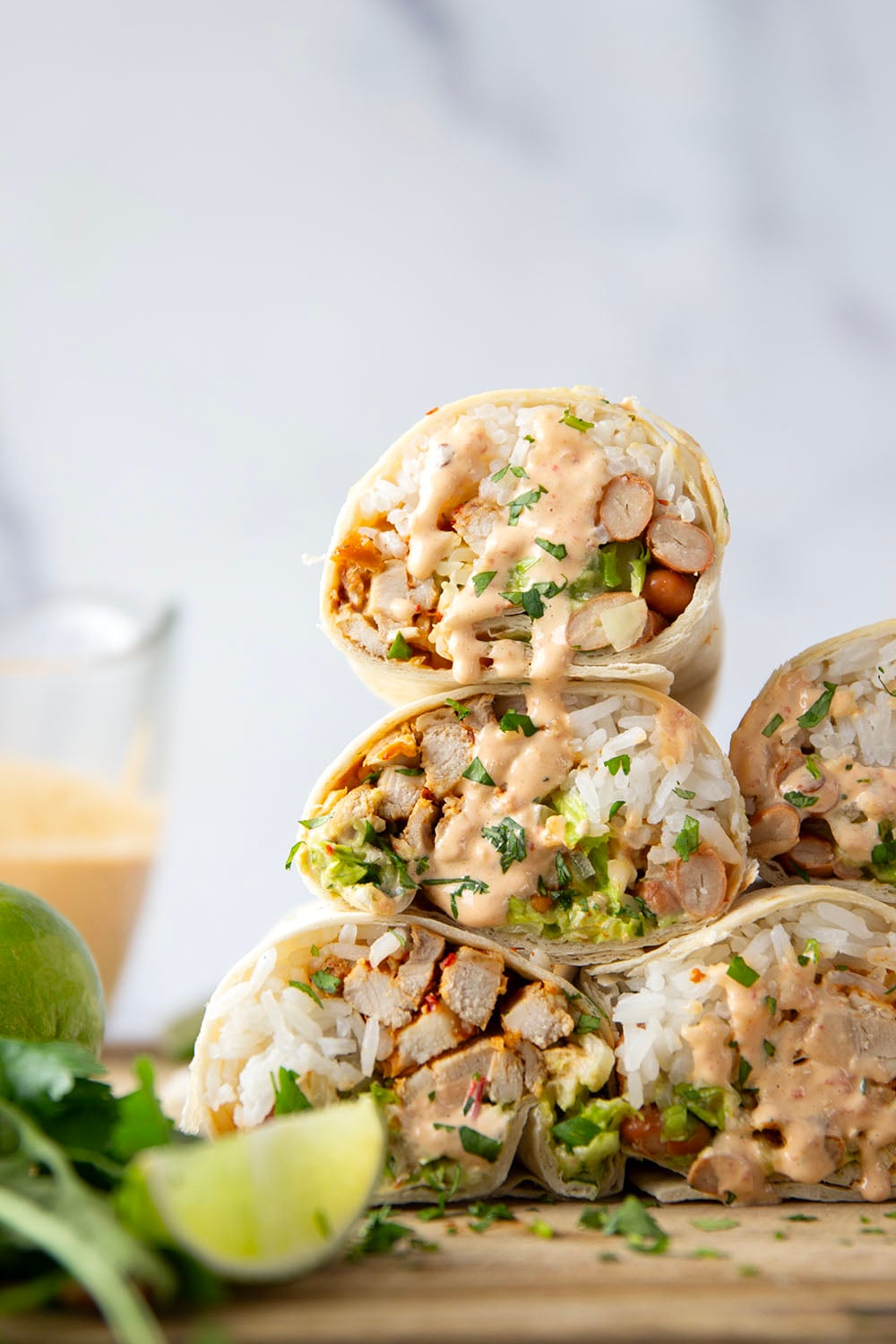These chipotle chicken burritos feature spicy chipotle marinated chicken, fluffy rice, pinto beans, shredded lettuce, and a creamy chipotle sauce layered in soft flour tortillas.