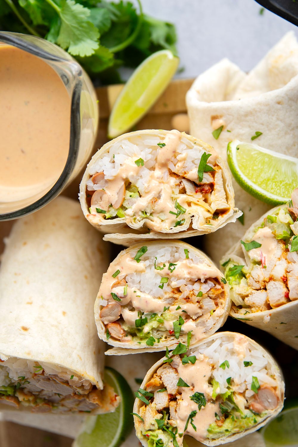 These chipotle chicken burritos feature spicy chipotle marinated chicken, fluffy rice, pinto beans, shredded lettuce, and a creamy chipotle sauce layered in soft flour tortillas.