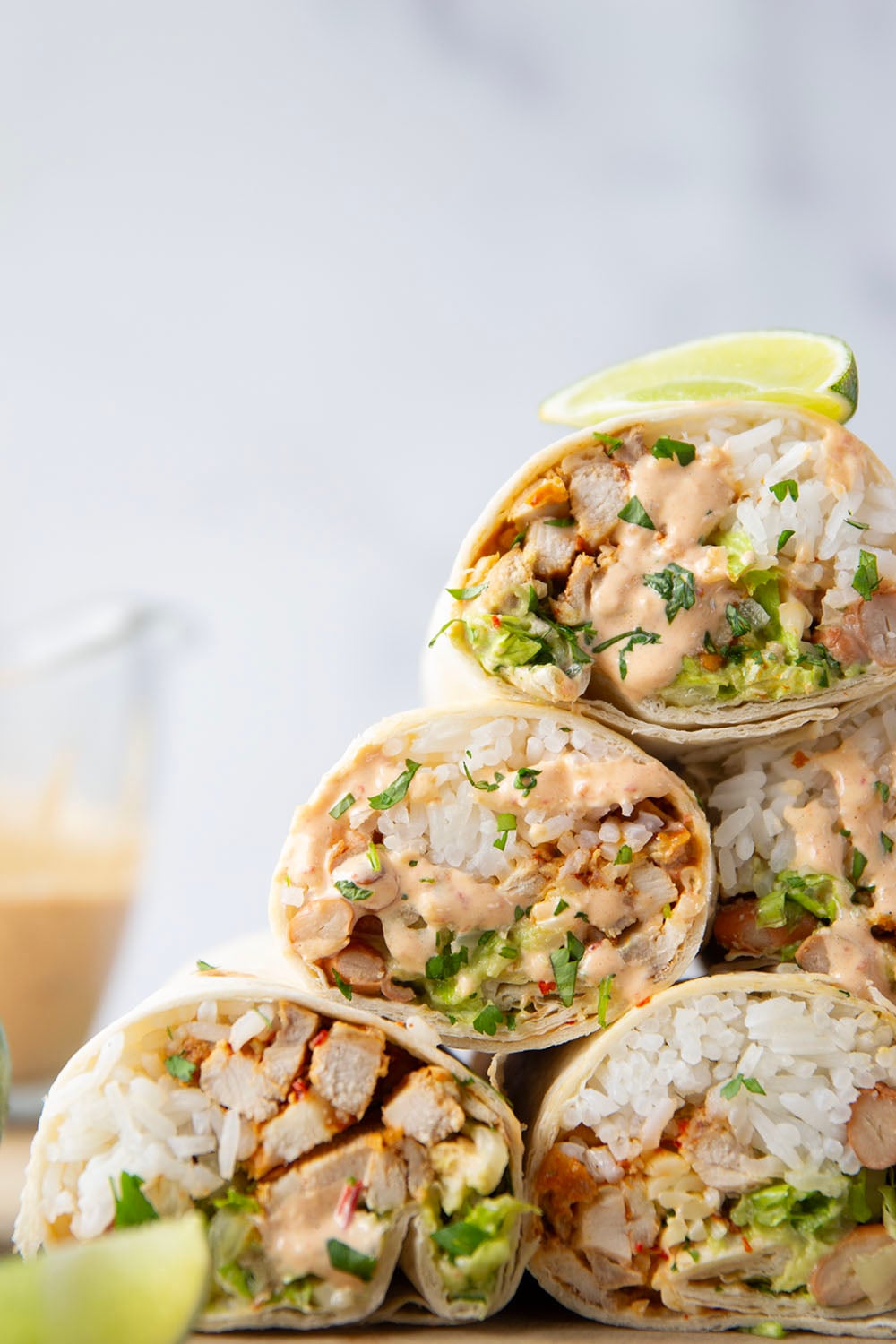 These chipotle chicken burritos feature spicy chipotle marinated chicken, fluffy rice, pinto beans, shredded lettuce, and a creamy chipotle sauce layered in soft flour tortillas.