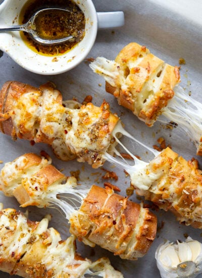 This cheesy garlic hasselback bread is baked with gooey mozzarella and Parmesan between slices and brushed in a garlicky herb butter.