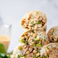 These chipotle chicken burritos feature spicy chipotle marinated chicken, fluffy rice, pinto beans, shredded lettuce, and a creamy chipotle sauce layered in soft flour tortillas.