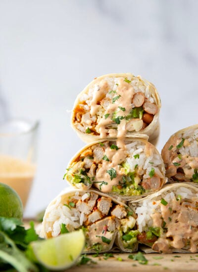 These chipotle chicken burritos feature spicy chipotle marinated chicken, fluffy rice, pinto beans, shredded lettuce, and a creamy chipotle sauce layered in soft flour tortillas.