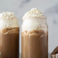 Chase away the winter chill with this eggnog hot chocolate that features winter spices, rich eggnog, and sweet hot chocolate all in one drink! Enjoy this easy holiday sipper hot or cold with lots of whipped cream on top.