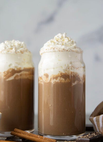 Chase away the winter chill with this eggnog hot chocolate that features winter spices, rich eggnog, and sweet hot chocolate all in one drink! Enjoy this easy holiday sipper hot or cold with lots of whipped cream on top.