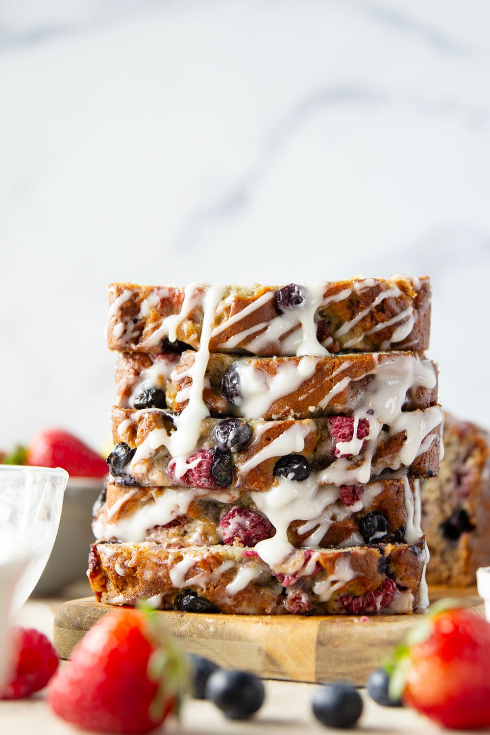 Soft and moist berry banana bread is packed with fresh strawberries, raspberries, and blueberries and topped with a rich cream cheese icing.