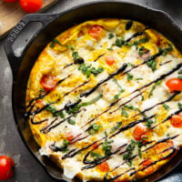 This caprese frittata couldn't be easier to whip up and features a base of fluffy eggs, sweet cherry tomatoes, gooey fresh mozzarella, and lots of fresh basil and balsamic glaze on top.