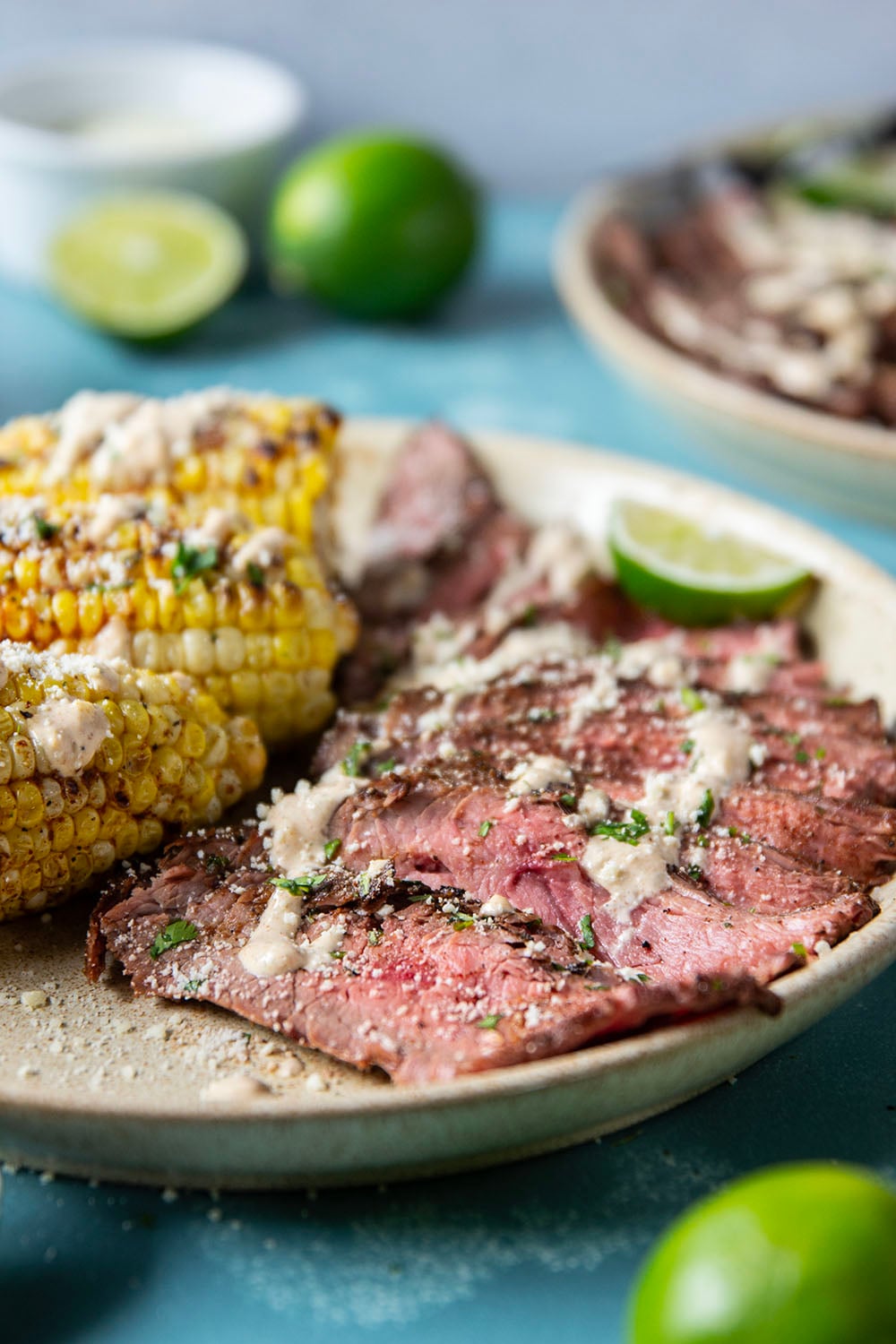 Spice-rubbed grilled flank steak and corn is an easy summer dish that pairs very well with a creamy chili lime sauce drizzled on top.