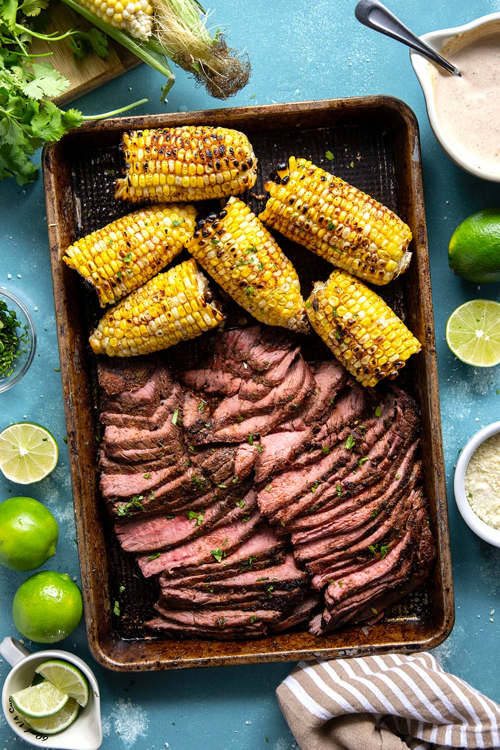 Spice-rubbed grilled flank steak and corn is an easy summer dish that pairs very well with a creamy chili lime sauce drizzled on top.