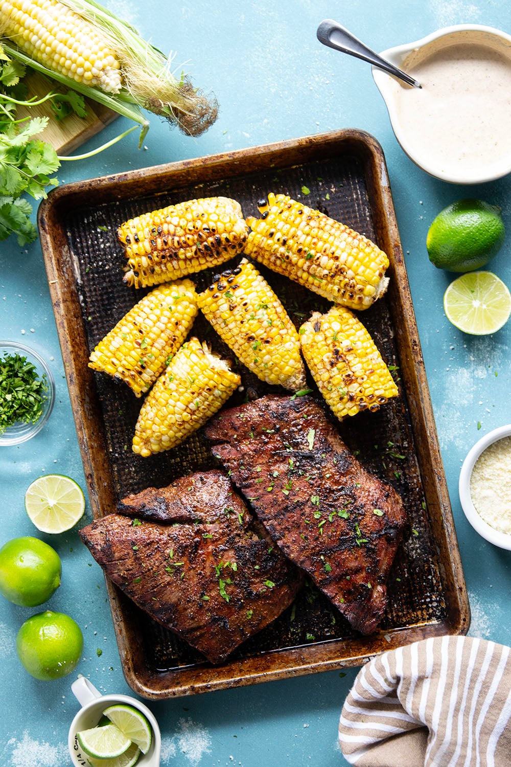 Spice-rubbed grilled flank steak and corn is an easy summer dish that pairs very well with a creamy chili lime sauce drizzled on top.