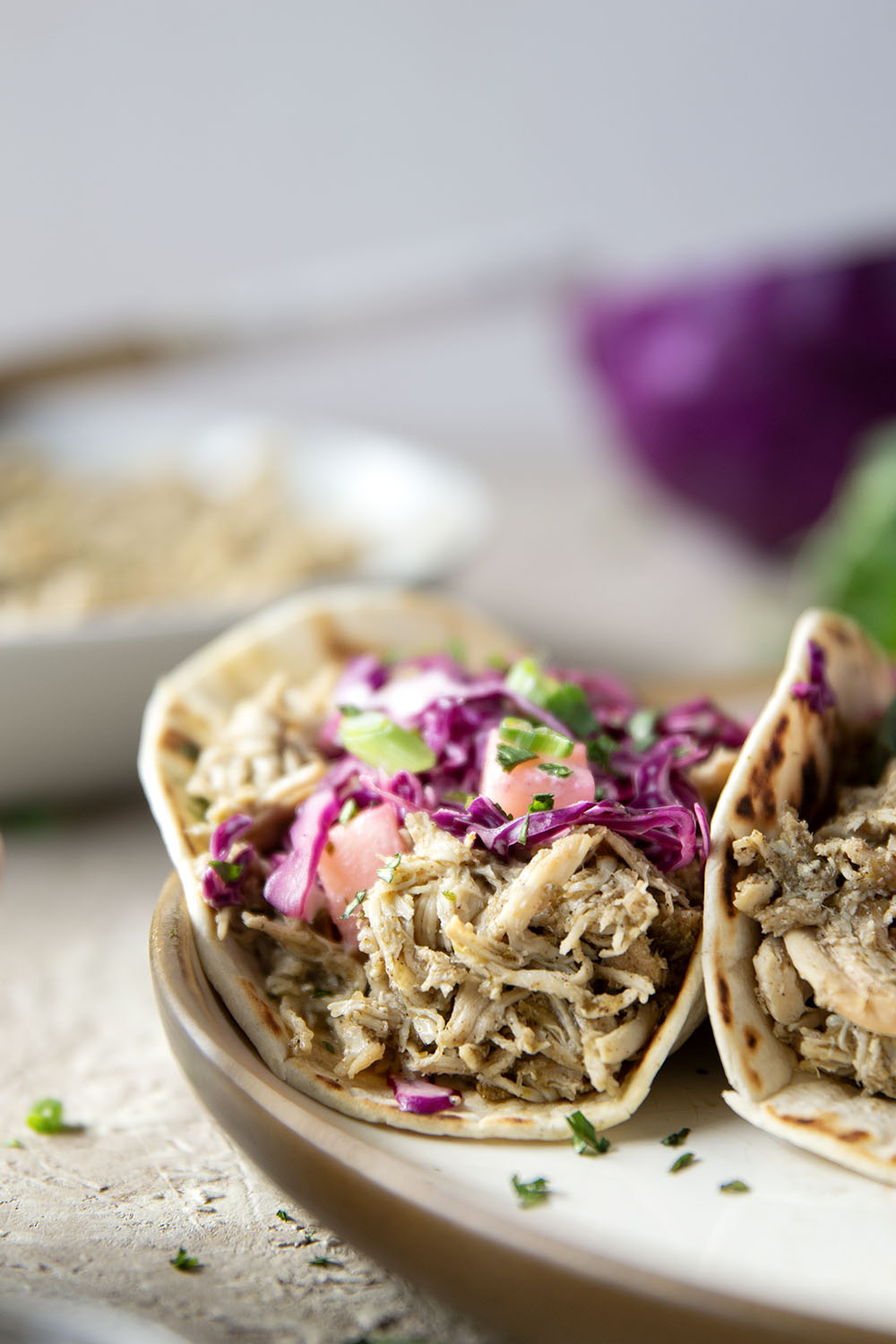 Spicy slow-cooked jerk chicken tacos feature fall-apart tender chicken cooked in a spicy homemade jerk sauce and topped with a fresh pineapple slaw.