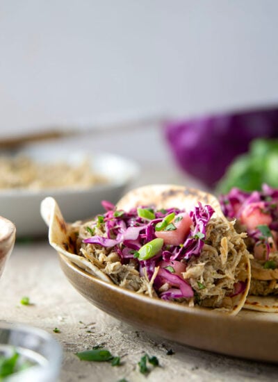 Spicy slow-cooked jerk chicken tacos feature fall-apart tender chicken cooked in a spicy homemade jerk sauce and topped with a fresh pineapple slaw.