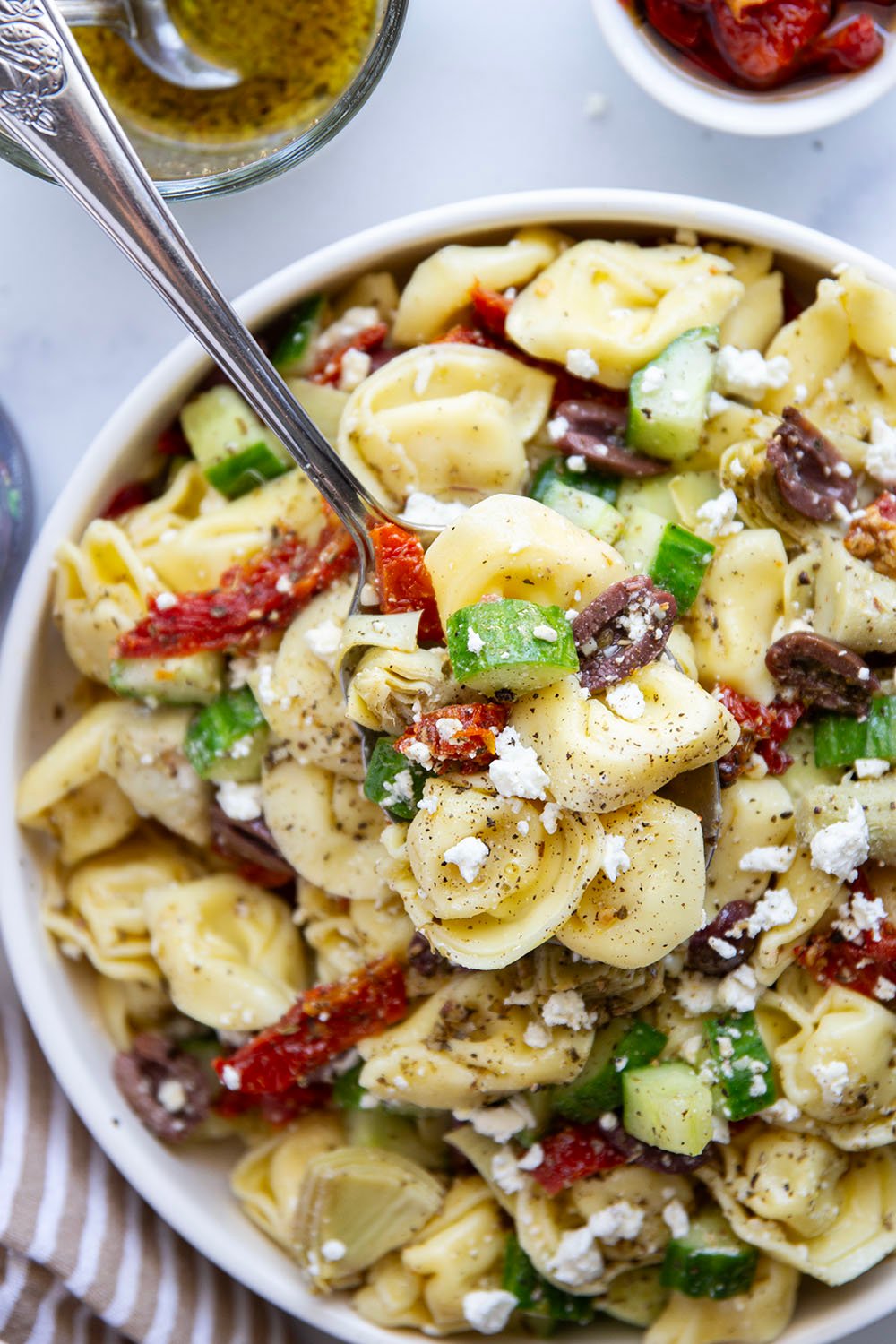 Bring this fresh Mediterranean tortellini pasta salad to any picnic and watch it disappear! Loaded with a rainbow of Mediterranean ingredients and tossed in a tangy white wine vinaigrette.
