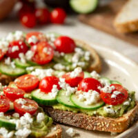 This Greek avocado toast is quick and easy enough for any kind of breakfast occasion! Pile toasted bread slices with silky mashed avocado, crisp cucumber slices, lots of fresh cherry tomatoes, and feta.