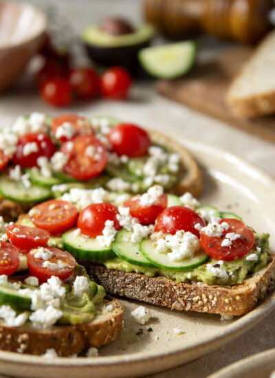 This Greek avocado toast is quick and easy enough for any kind of breakfast occasion! Pile toasted bread slices with silky mashed avocado, crisp cucumber slices, lots of fresh cherry tomatoes, and feta.
