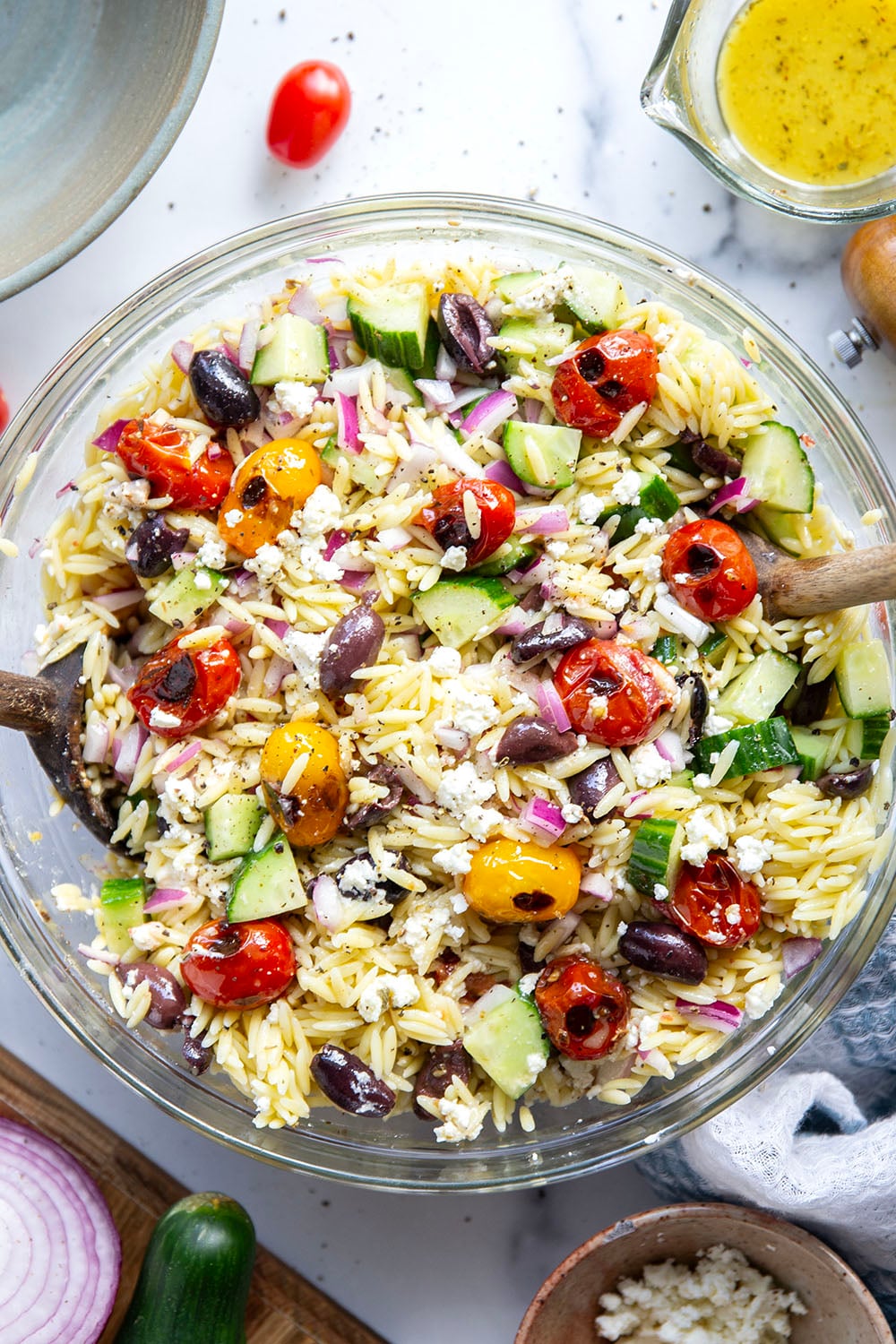 This colorful Greek orzo pasta salad is loaded with plenty of charred cherry tomatoes, crunchy cucumbers, lots of fresh feta, and tossed in a flavorful red wine vinaigrette for one stunning summer salad!