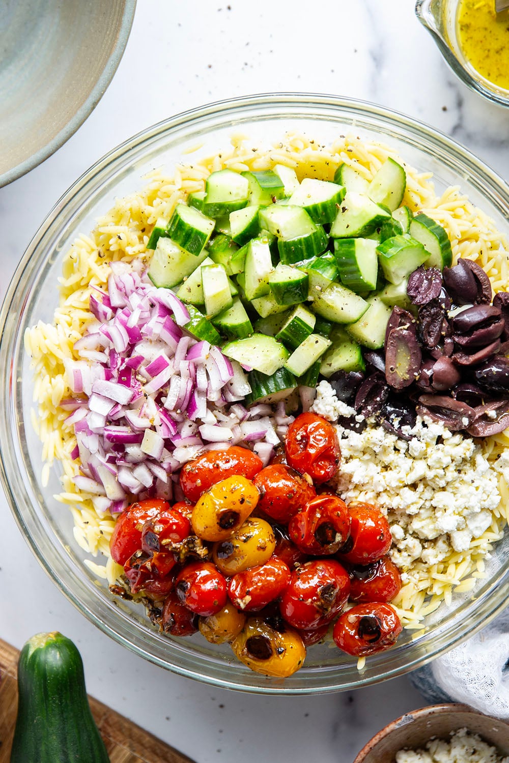 This colorful Greek orzo pasta salad is loaded with plenty of charred cherry tomatoes, crunchy cucumbers, lots of fresh feta, and tossed in a flavorful red wine vinaigrette for one stunning summer salad!