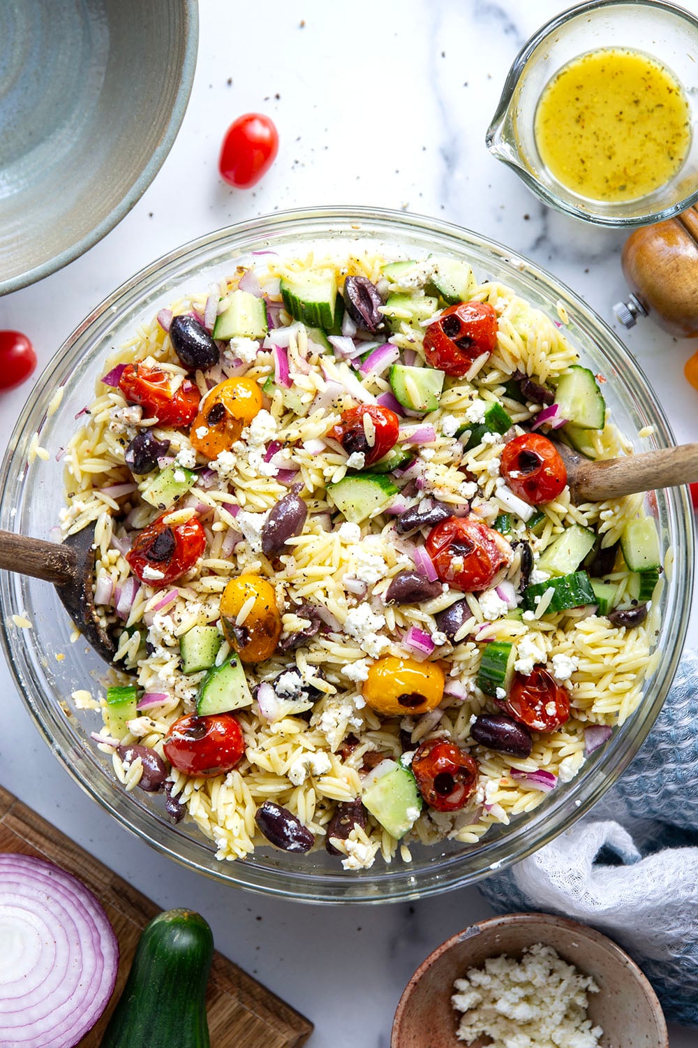 This colorful Greek orzo pasta salad is loaded with plenty of charred cherry tomatoes, crunchy cucumbers, lots of fresh feta, and tossed in a flavorful red wine vinaigrette for one stunning summer salad!