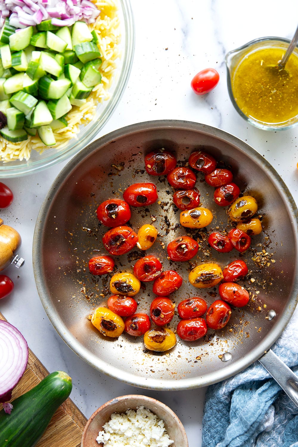 This colorful Greek orzo pasta salad is loaded with plenty of charred cherry tomatoes, crunchy cucumbers, lots of fresh feta, and tossed in a flavorful red wine vinaigrette for one stunning summer salad!
