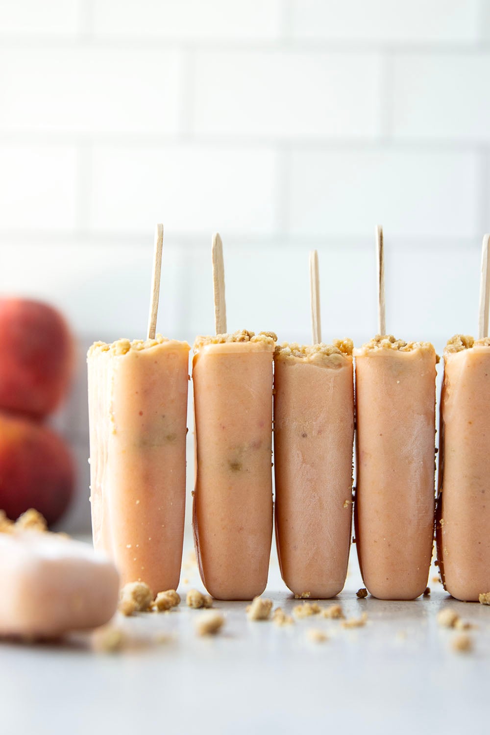Juicy summer peaches and a crunchy brown sugar streusel are the perfect match in these multi-layered peach popsicles!