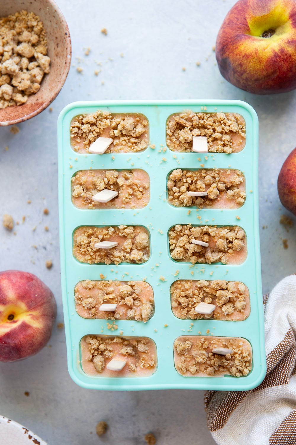 Juicy summer peaches and a crunchy brown sugar streusel are the perfect match in these multi-layered peach popsicles!