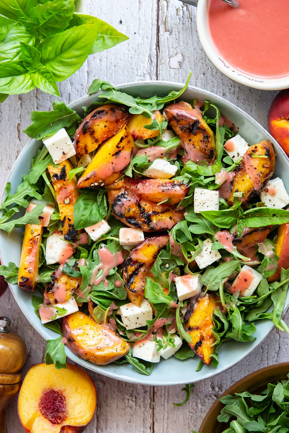 This peach arugula summer salad is loaded to the max with sweet grilled peach wedges, soft mozzarella cubes, and the most incredible homemade raspberry vinaigrette.