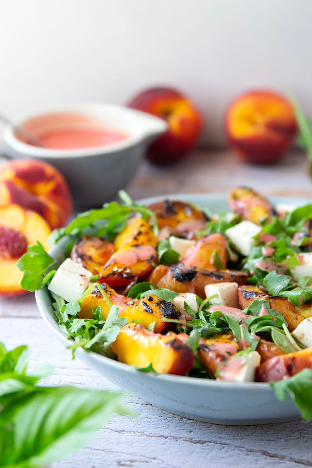 This peach arugula summer salad is loaded to the max with sweet grilled peach wedges, soft mozzarella cubes, and the most incredible homemade raspberry vinaigrette.