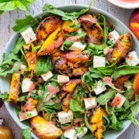 This peach arugula summer salad is loaded to the max with sweet grilled peach wedges, soft mozzarella cubes, and the most incredible homemade raspberry vinaigrette.