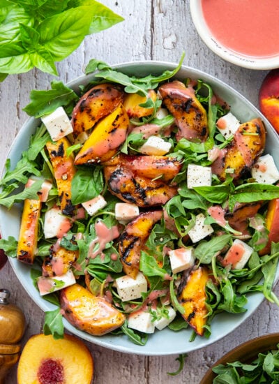 This peach arugula summer salad is loaded to the max with sweet grilled peach wedges, soft mozzarella cubes, and the most incredible homemade raspberry vinaigrette.