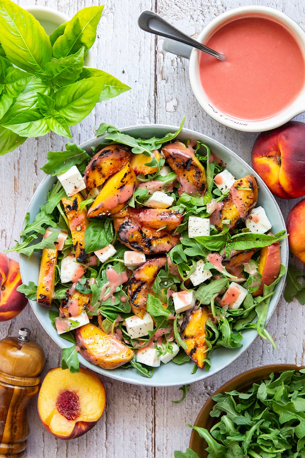 This peach arugula summer salad is loaded to the max with sweet grilled peach wedges, soft mozzarella cubes, and the most incredible homemade raspberry vinaigrette.