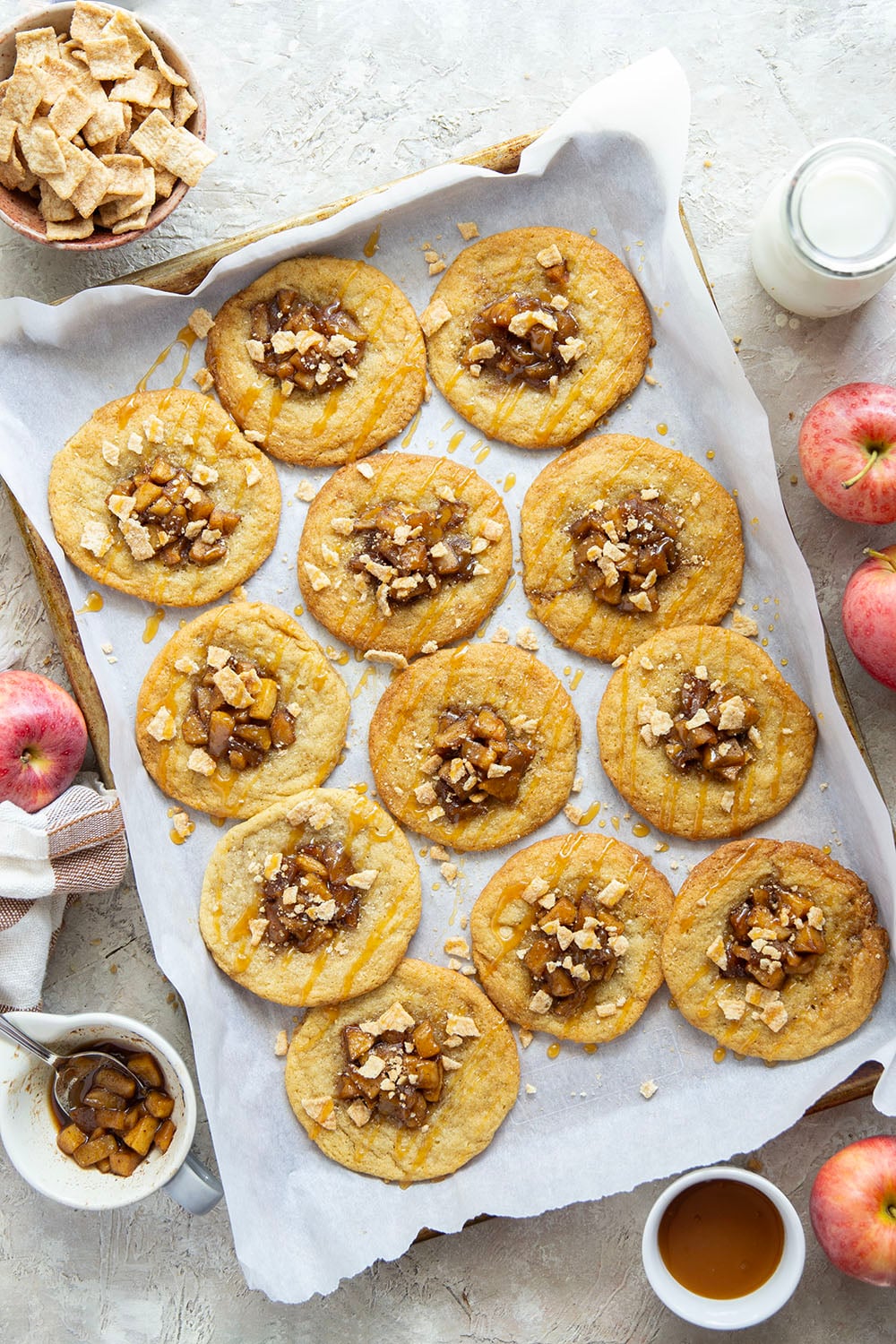These caramel apple pie cookies feature a soft and chewy butter cookie base with a caramelized apple center, rich drizzles of caramel sauce, and crushed cinnamon crunch cereal on top.