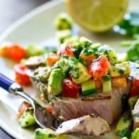 Tender tuna steaks are marinated in cilantro and lots of lime, grilled until perfectly smoky, and topped with an amazing fresh avocado cucumber salsa for one easy summer dinner!