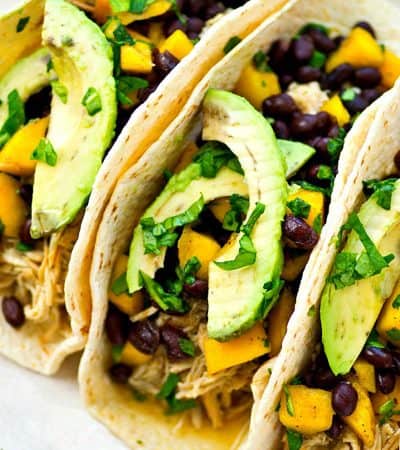 Up your taco night game with these INSANELY-easy crockpot green chile chicken tacos! The chicken is unbelievably tender and a mango black bean salsa piled on top brings tons of flavor!