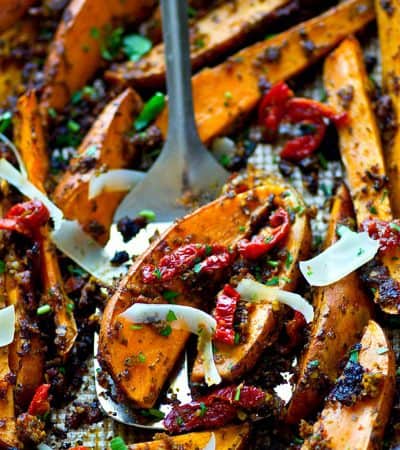 Roasted in a flavorful homemade sun-dried tomato pesto and covered in shaved Parmesan, these sweet potato wedges are SUCH an easy dinner side and you'll be eating them straight off the pan.