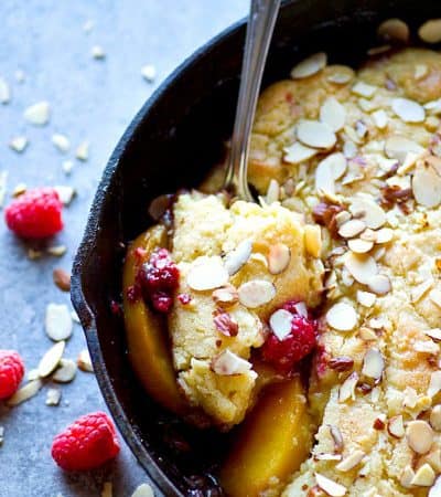 Juicy peaches and raspberries are topped with a cookie-like almond topping and it's all baked in your skillet! This raspberry almond peach cobbler is seriously the best summer dessert ever.