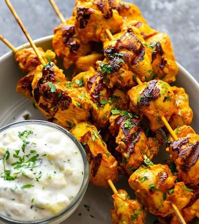 Hands down the BEST grilled tandoori chicken skewers you will ever throw on the grill this summer. The secret is in the SUPER flavorful long marinade and homemade tzatziki sauce.