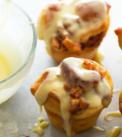 Fluffy cinnamon roll muffins are stuffed with a caramelized apple filling and glazed in a sweet white chocolate glaze for a dreamy fall breakfast!