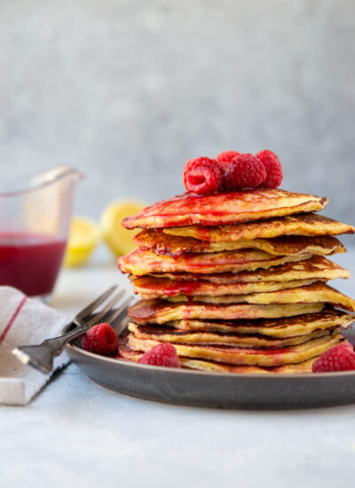 Incredibly soft and airy lemon cottage cheese pancakes are topped with a tangy homemade raspberry syrup for an unforgettable stack! Only a handful of ingredients needed and they're naturally gluten-free.