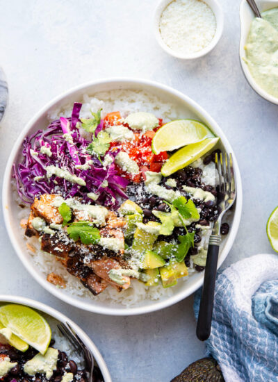 These salmon taco bowls feature everything you love about a fish taco in rice bowl form! Loaded with lots of spicy blackened salmon, hearty rice, a creamy tahini cilantro sauce, and all your favorite toppings.