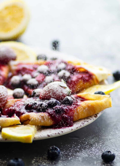 Mixed berry cream cheese crepes feature perfectly lacy homemade crepes, a tangy lemon cream cheese filling, and a fresh mixed berry sauce on top.