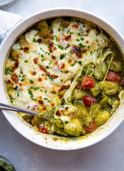 Baked with two kinds of cheese on top with lots of tender zucchini and cherry tomatoes, this cheesy baked pesto gnocchi uses basic pantry ingredients and is ready in under an hour!