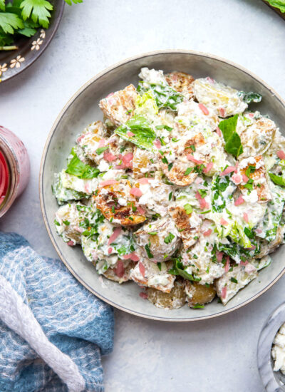 This Greek tzatziki potato salad features tender herb-roasted potatoes dressed with homemade tzatziki sauce and tossed with lots of crisp lettuce, crumbly feta, and pickled red onions.
