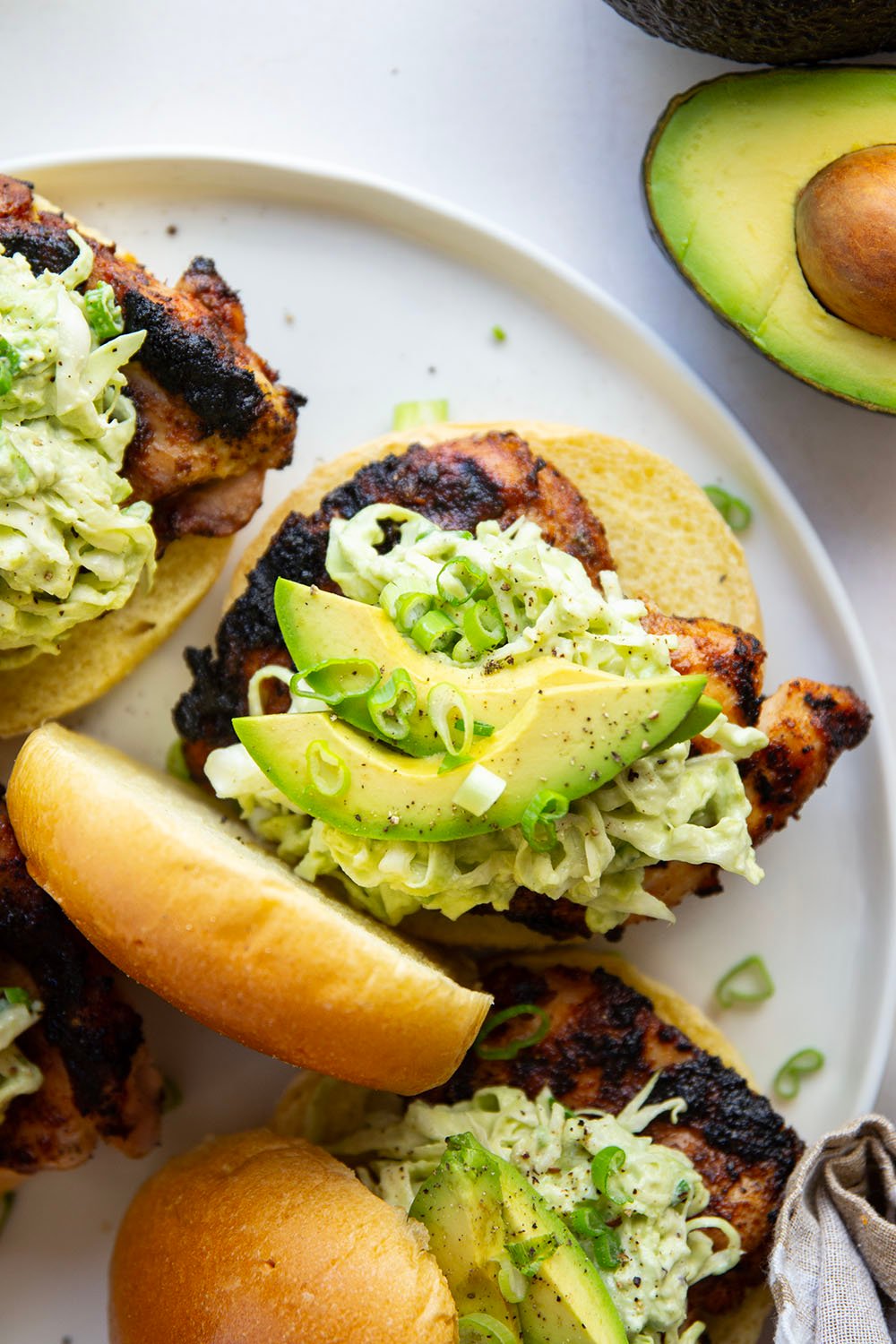Juicy grilled blackened chicken thighs are stuffed between buns with lots of creamy avocado slaw. This blackened chicken sandwich will quickly become a favorite!