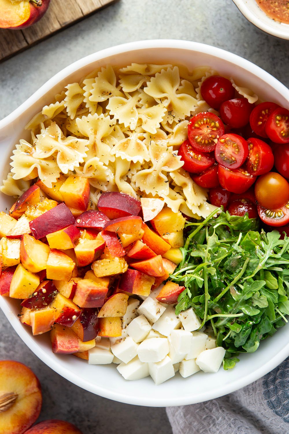 Sweet peaches pair perfectly with herby basil, soft mozzarella, juicy cherry tomatoes, and a tangy balsamic dressing in this peach caprese pasta salad.