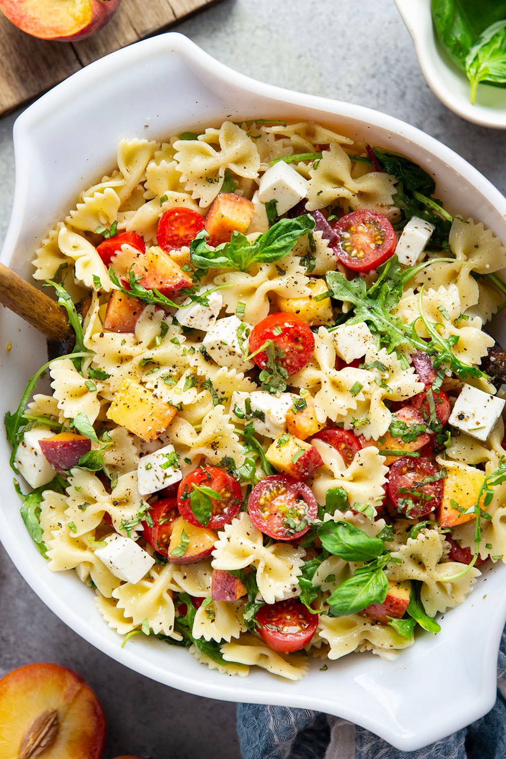 Sweet peaches pair perfectly with herby basil, soft mozzarella, juicy cherry tomatoes, and a tangy balsamic dressing in this peach caprese pasta salad.