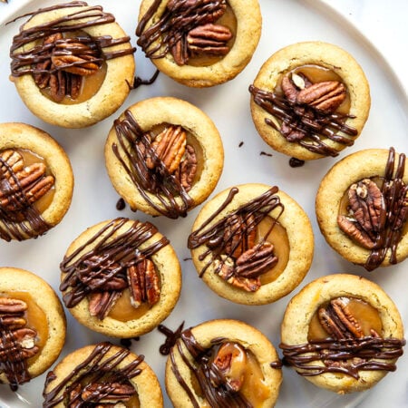 These soft and chewy turtle cookie cups feature a soft butter cookie cup filled with toasted pecans, salted caramel, and a luscious drizzle of melted chocolate.