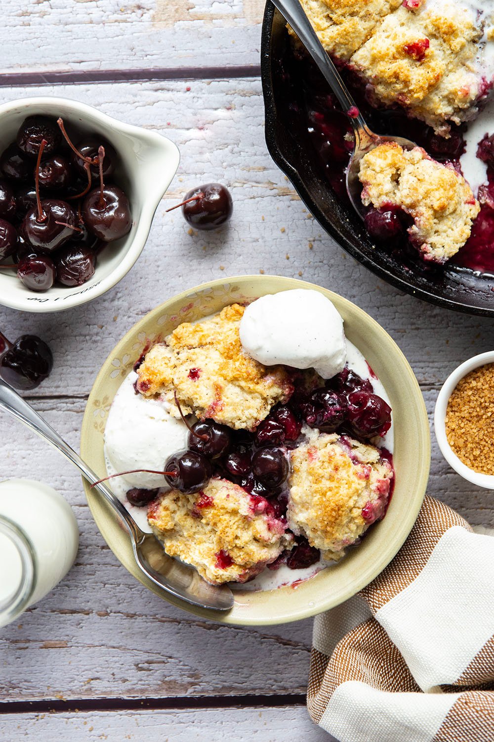 This cherry cobbler features a juicy fresh cherry filling baked with flaky browned butter biscuits on top. An incredible summer dessert warm from the oven with vanilla ice cream on top!